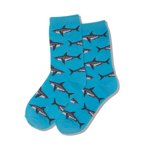 Child wearing blue socks with shark pattern playing Scrabble on a textured surface.
