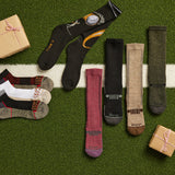 Collection of socks with brand name on a grass-like surface with small gift boxes.