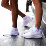 Two pairs of white sneakers worn by different people on a concrete surface. thumbnail