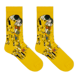 A pair of bright yellow crew socks featuring a printed art design inspired by Gustav Klimt's 'The Kiss', shown against a plain white background.