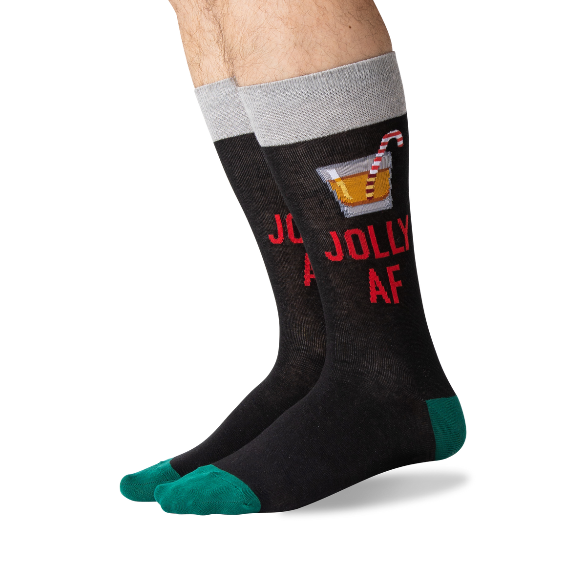 A pair of novelty crew socks worn on a person's feet, featuring a dark charcoal body with red text reading 'JOLLY AF', a cocktail graphic, a gray cuff, and teal toes and heels.