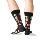 A pair of black crew socks with a colorful Christmas gingerbread pattern, worn on a person's legs against a white background.