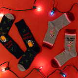 Two pairs of festive socks on a red background with Christmas lights.