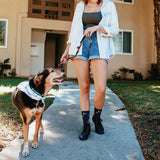 Woman walking a dog on a leash in front of a house
