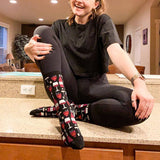 Person sitting on a counter wearing black tights and patterned socks with a wine design.