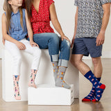 Three people sitting on a white block, wearing colorful patterned socks. thumbnail