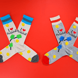 Two pairs of pickleball-themed socks on a red background thumbnail