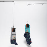 Two pairs of socks with fishing-themed designs hanging on a white background thumbnail