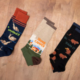 Three pairs of socks with humorous designs on a wooden surface