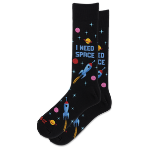 A pair of black crew socks with a colorful space-themed print featuring rockets, planets, stars, and the text 'I NEED SPACE'.