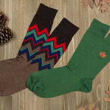 Two pairs of socks with different fall designs on a wooden surface. thumbnail