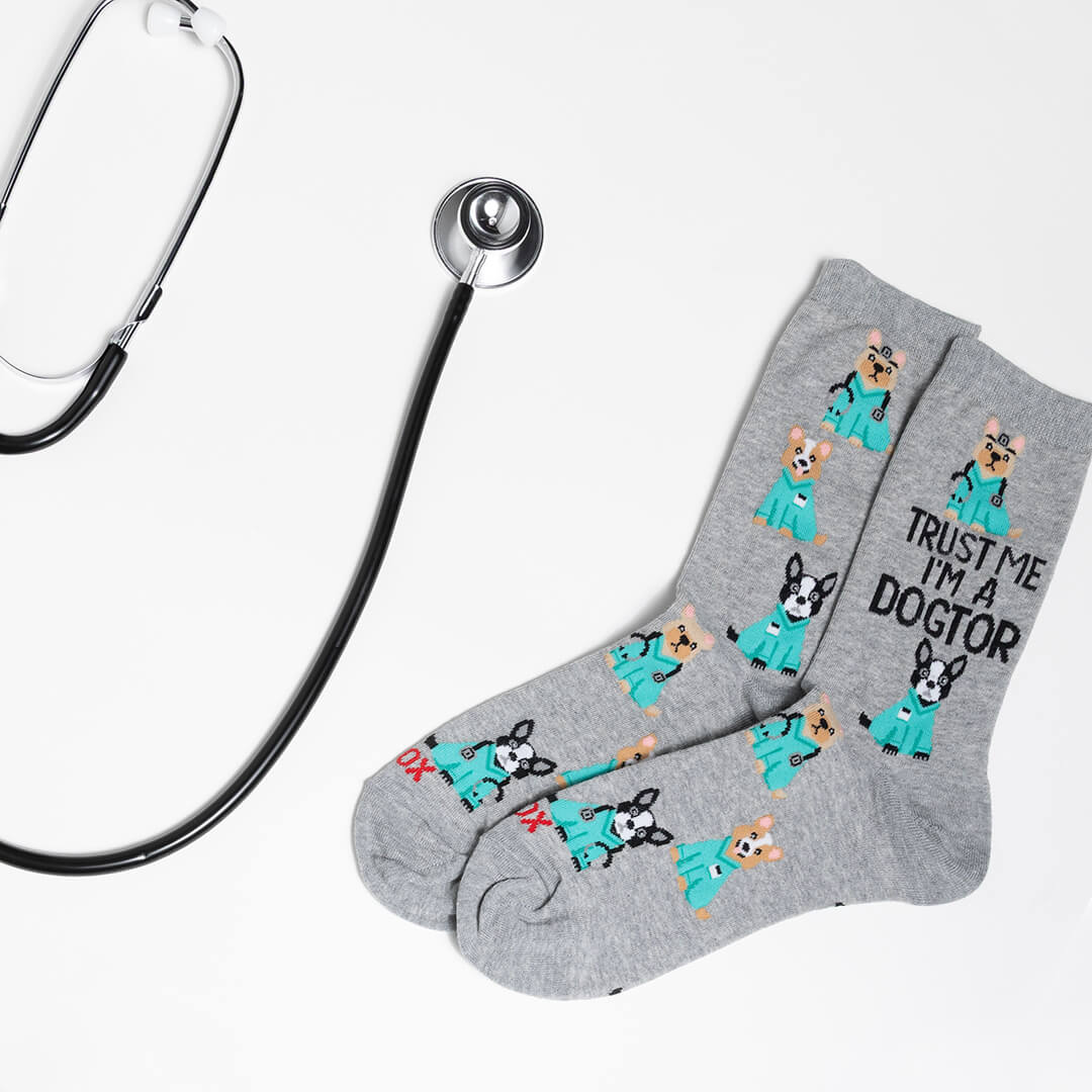 Gray socks with dog illustrations and text, paired with a stethoscope on a light gray background