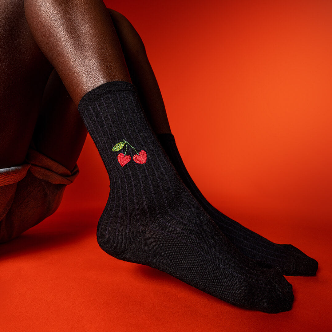 Black socks with red cherry design on a red background
