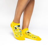 A person wearing bright yellow low-cut socks with a black, white, and gold abstract art print, shown against a plain white studio background.