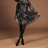 Woman wearing a floral dress with black tights and heels on a brown background thumbnail
