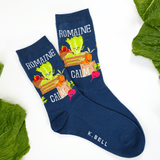 Navy blue socks with vegetable design and 'K. Bell' branding on a white background with green leaves.