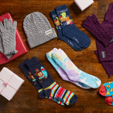 Collection of winter accessories including hats, gloves, and socks on a wooden surface. thumbnail
