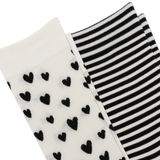 Two pairs of knit socks shown on a white background: one pair is off-white with scattered black heart motifs, and the other pair is black and white striped.