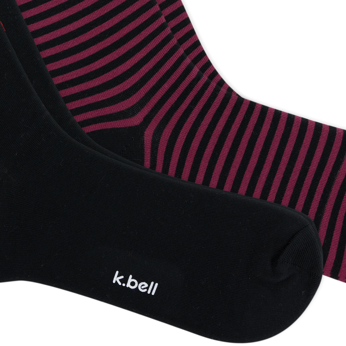 Close-up of two pairs of socks, with one sock in solid black showing the white 'k.bell' logo and the other showing a black and dark pink striped pattern.