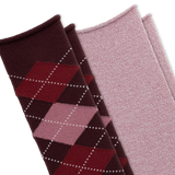 Two pairs of knit socks arranged diagonally on a white background. The front pair is dark burgundy with an argyle pattern in red, pink, and white dotted lines. The back pair is a solid light heathered pink.