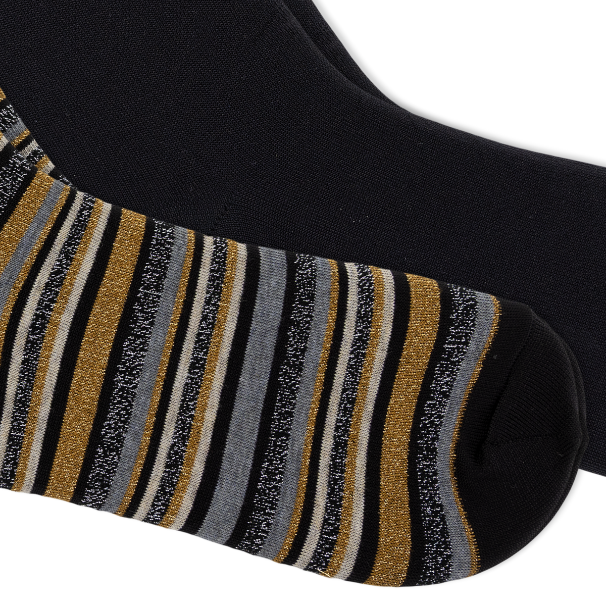 A close-up of a black sock with vertical glittery stripes in gold, gray, and black, and the second sock being solid black, shown against a plain white background.