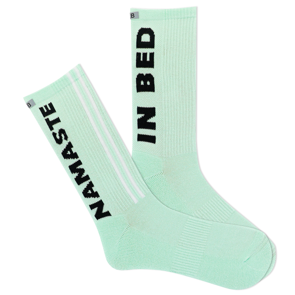 A pair of mint green sports crew socks with the text 'NAMASTE IN BED' printed on the side, featuring a reflective logo and a striped design with a visible logo on the calf area.