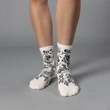 White socks with black floral patterns worn by a person on a gray background thumbnail