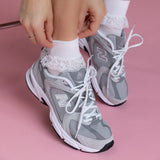 Person wearing gray sneakers with white laced ankle socks on a pink background thumbnail