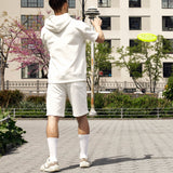 Person in white outfit playing with a yellow frisbee in an urban park setting thumbnail