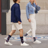 Two people walking on a sidewalk wearing denim jackets and white pants.