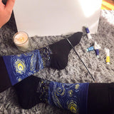 Person wearing socks with a Starry Night design on a textured surface with a candle and items.
