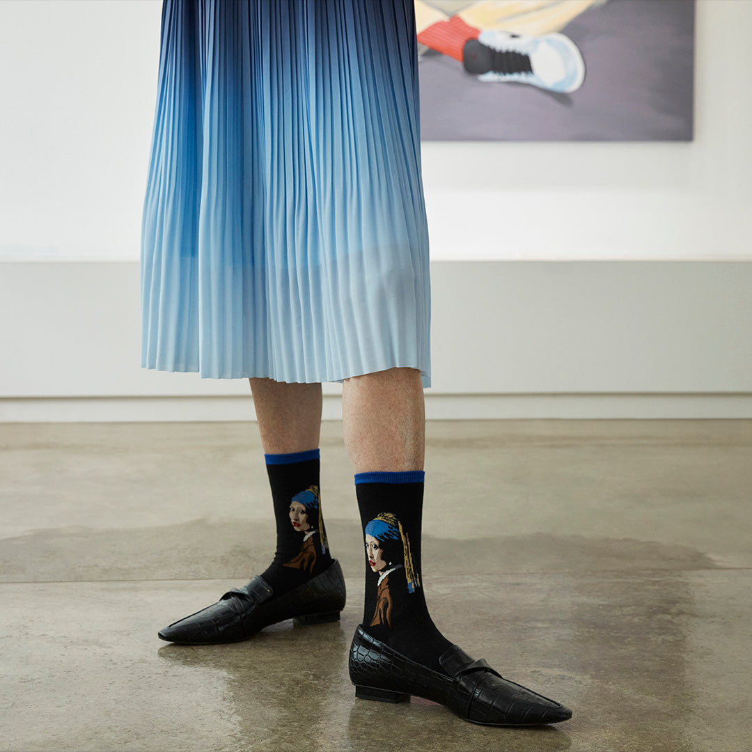 Person wearing socks with a design of a woman with a pearl earring in an indoor setting.