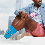 Man sitting outdoors with city skyline, wearing blue socks with hot dog design thumbnail