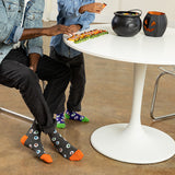 Two people sitting at a table with Halloween-themed decor, including a cauldron and jack-o'-lanterns.
