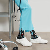 Person wearing light blue scrubs with patterned socks and white shoes, standing in a medical setting. thumbnail