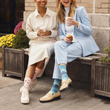 Two women sitting on a bench outdoors, wearing colorful socks.