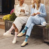 Two women sitting on a bench wearing colorful socks, one with pink polka dots and the other with a starry pattern.