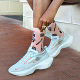 Person wearing light blue sneakers with transparent panels on a brick pavement. thumbnail