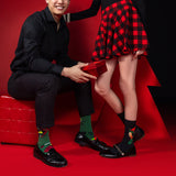 Man and woman on a red background wearing festive socks and shoes. thumbnail