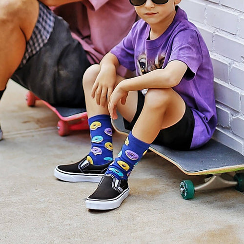 Child sitting on a skateboard wearing colorful socks with a brick wall background