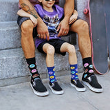 Person and child sitting on steps wearing colorful socks with donut and rainbow designs.