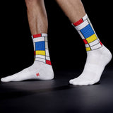 White socks with colorful Mondrian pattern worn by a person on a black background