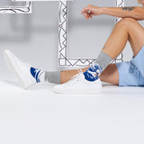 Person wearing white sneakers and patterned socks with Hokusai's 'The Wave' on a light gray background thumbnail