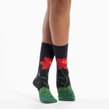 Black socks with red flower designs worn by a person on a white background
