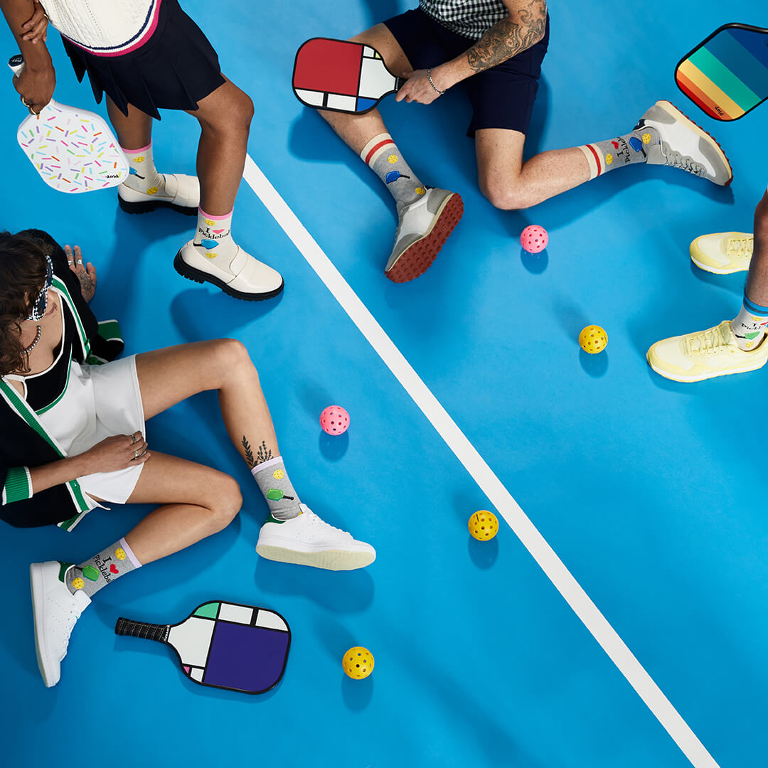 People playing with colorful pickleball paddles and balls on a blue court.