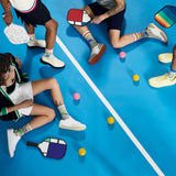 People playing with colorful pickleball paddles and balls on a blue court.
