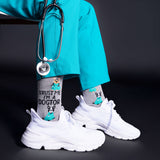 Person wearing white sneakers, gray socks with dog illustrations, and a teal outfit with a stethoscope.