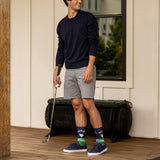 Man holding a golf club on a wooden deck with a neutral background thumbnail