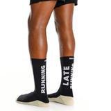 Black socks with 'RUNNING' and 'LATE RUNNING' text worn by a person on a white background thumbnail