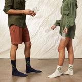 Two people wearing socks with recycling symbols, one in navy and the other in white, against a neutral background. thumbnail
